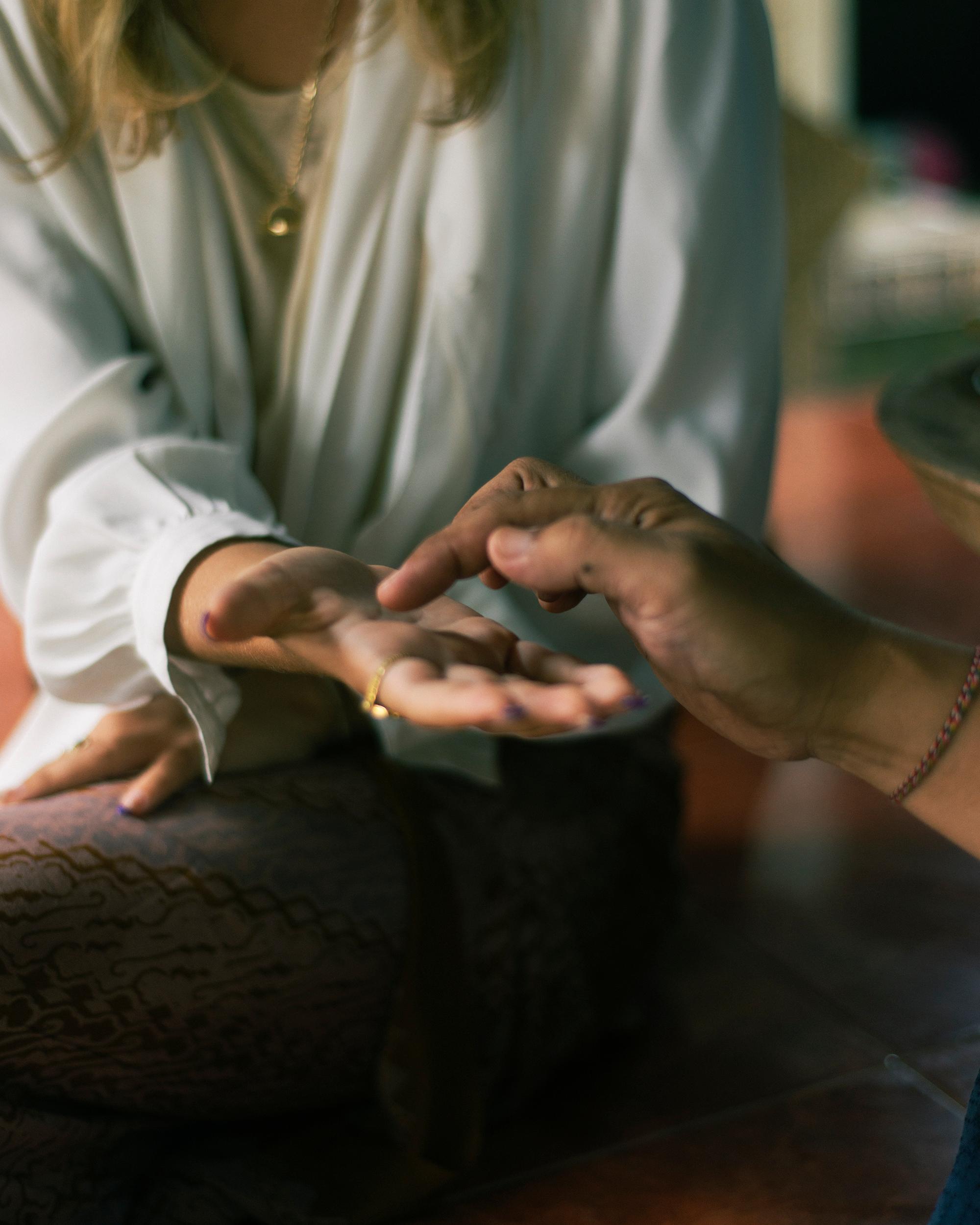 Hands engage in palm reading, serene ambiance, Banyan Tree Escape - Buahan Wellbeing.