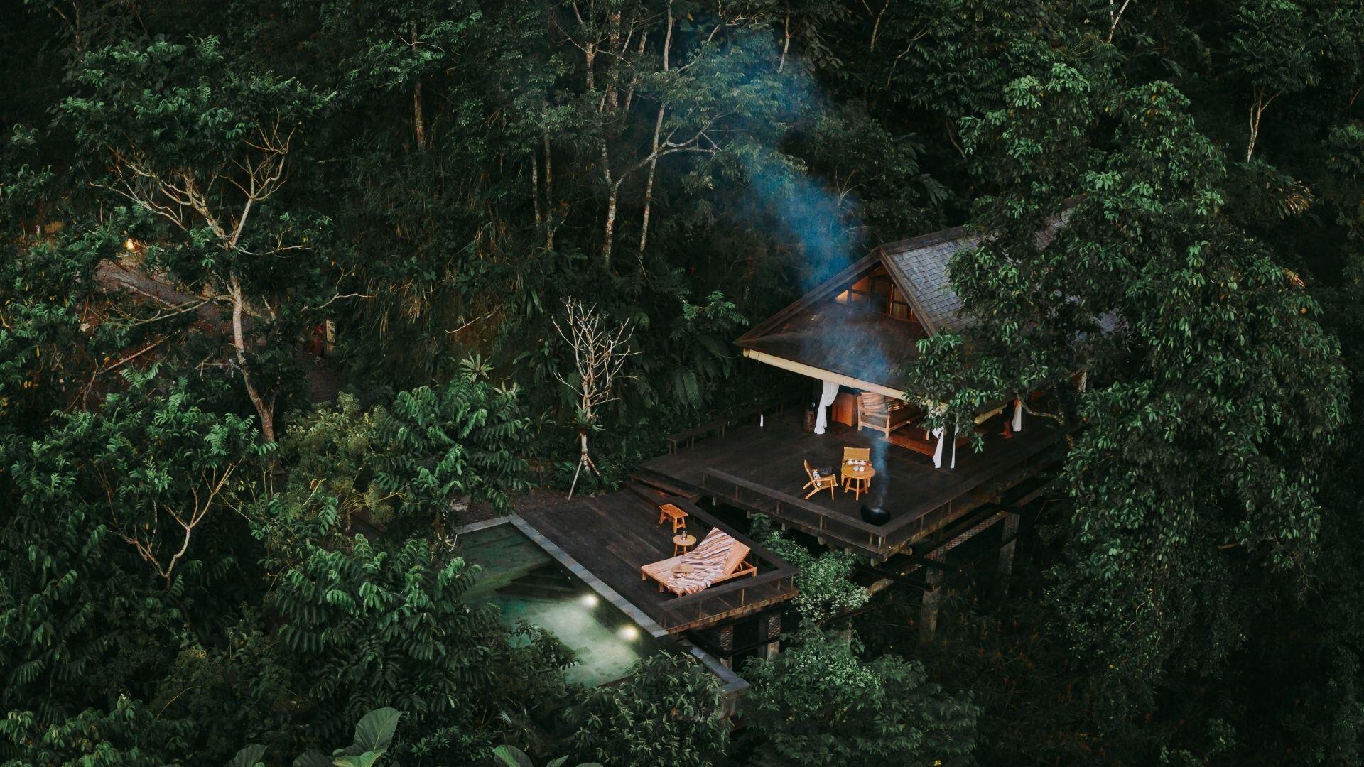 Secluded villa nestled in lush forest with patio and smoke rising, Banyan Tree Escape - Buahan.