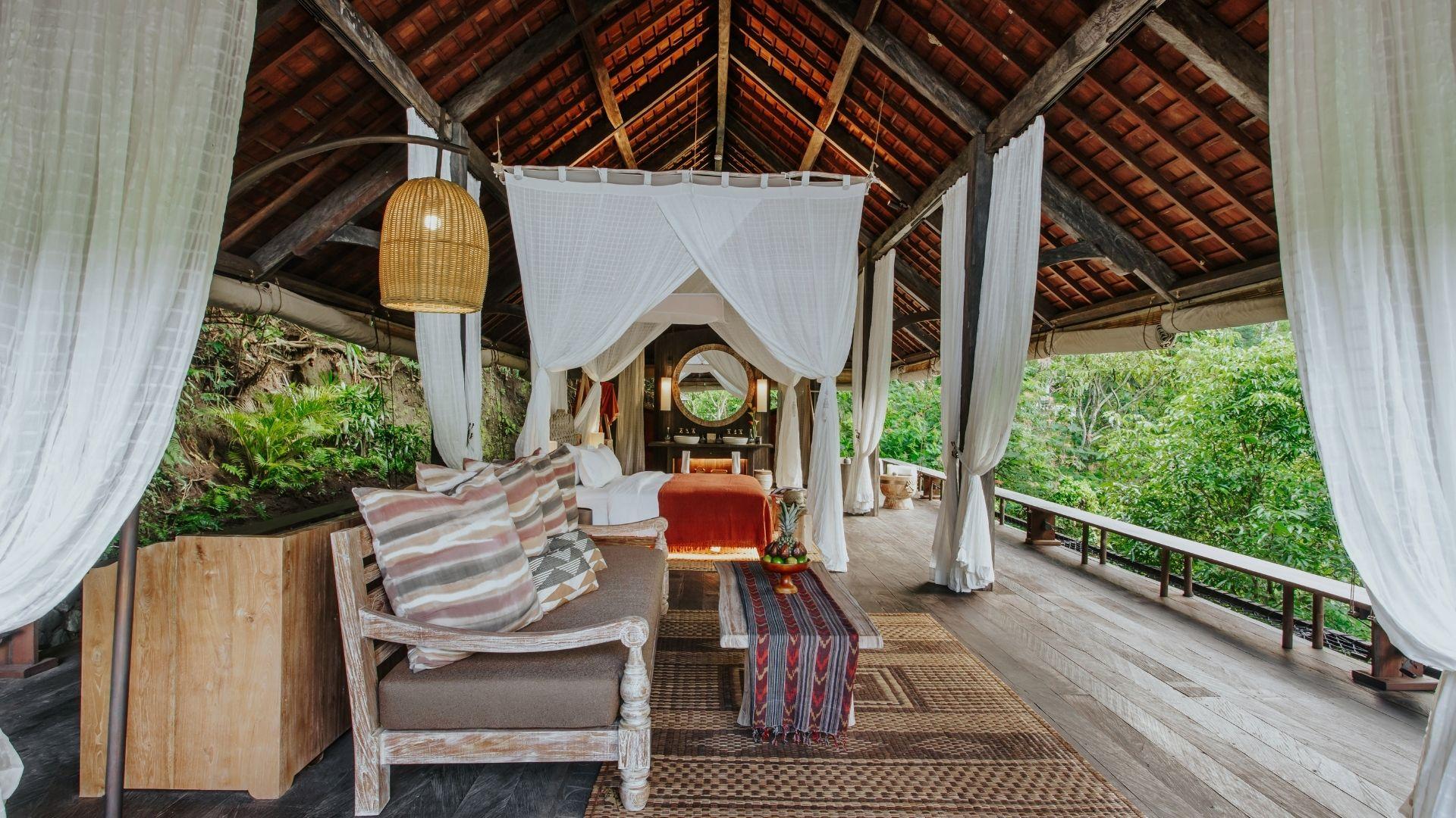 Open canopy bed with sheer curtains overlooks lush greenery at Banyan Tree Escape - Buahan accommodation.