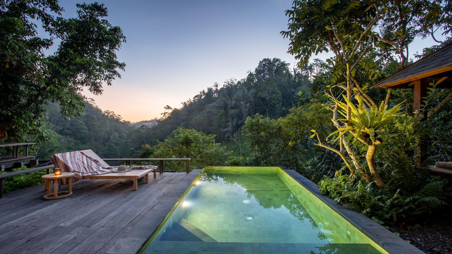 Banyan Tree Escape - Buahan villa nestled in lush jungle, with open deck and pool bale above the waterfall surrounded by trees.