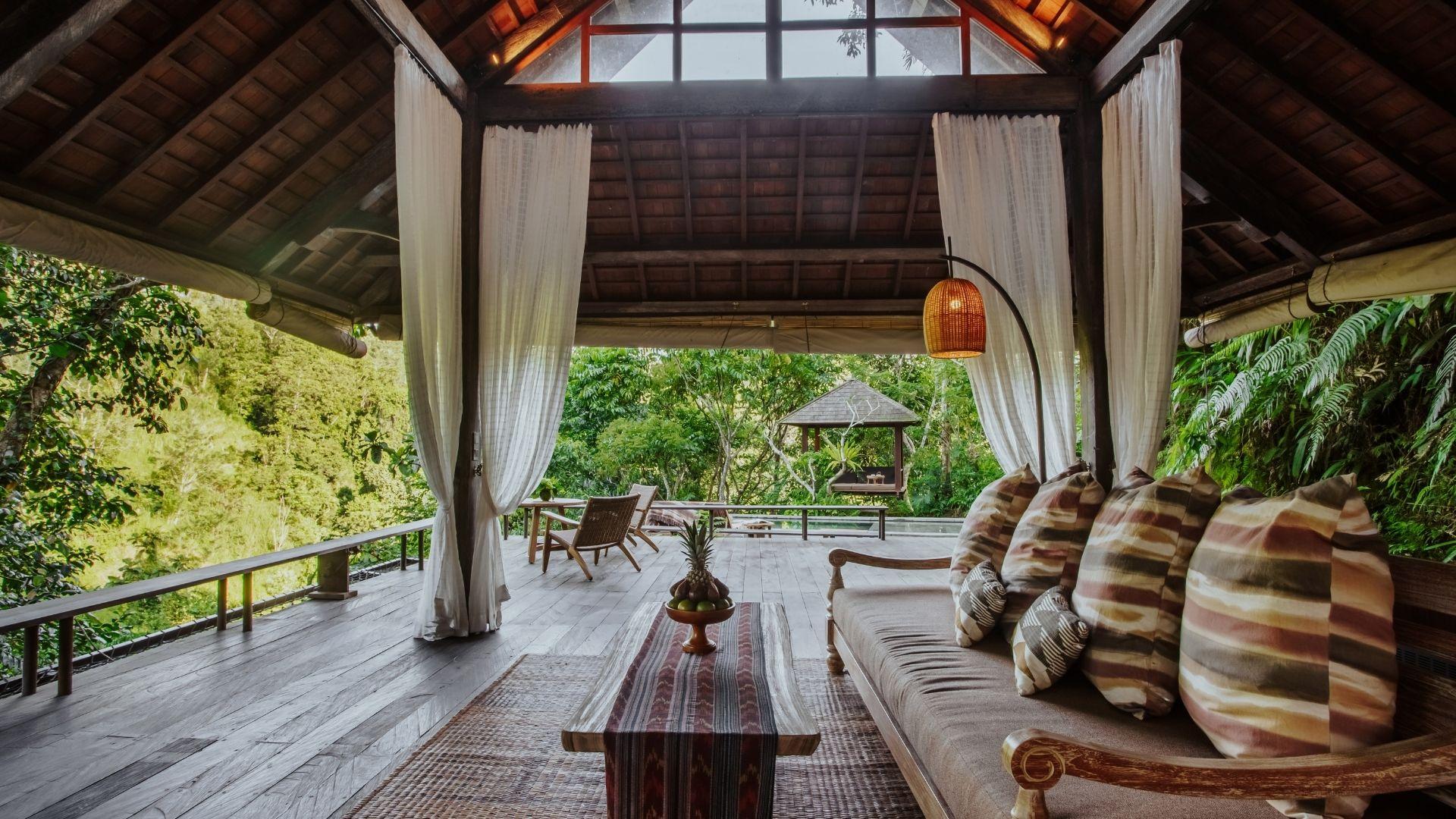 Open lounge with sofa overlooking lush greenery, blending nature and luxury at Banyan Tree Escape - Buahan.