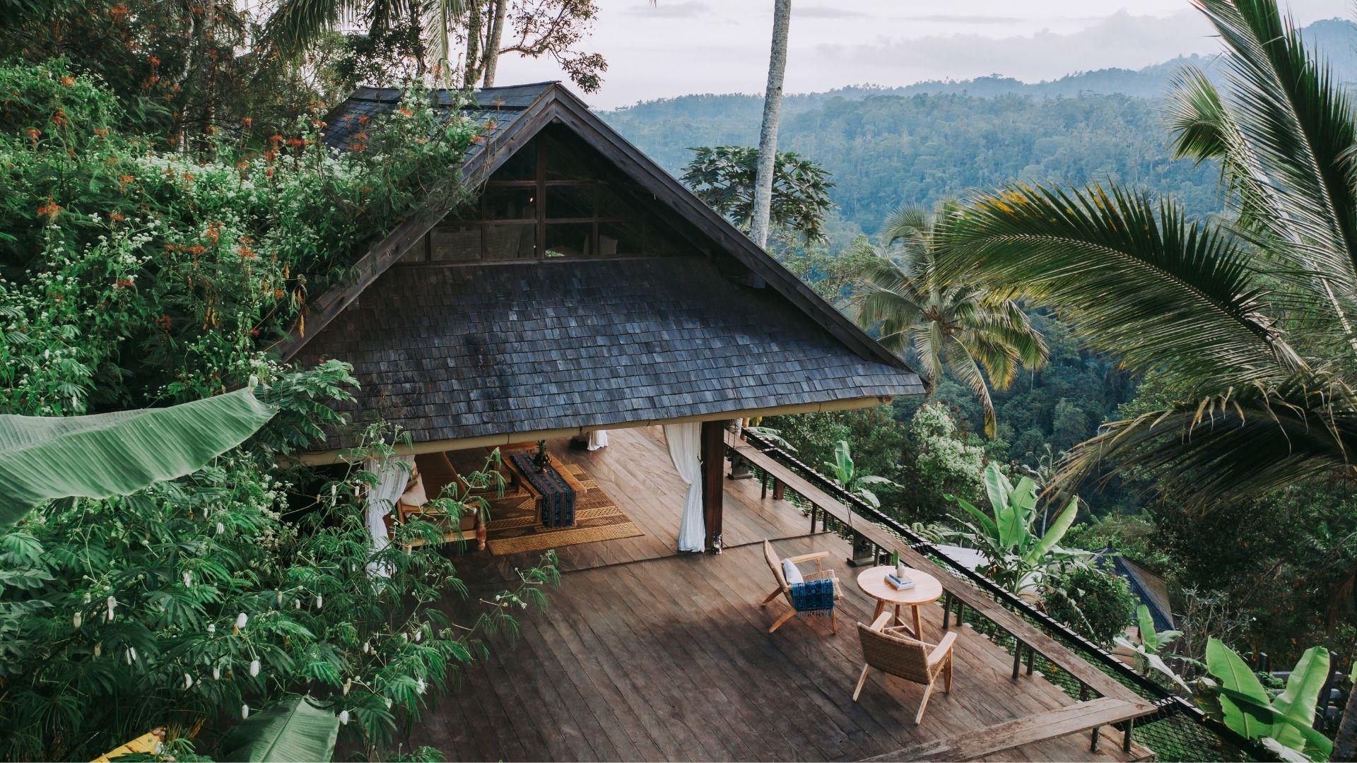 A rustic villa overlooks lush jungle greenery, featuring a wooden terrace at Banyan Tree Escape - Buahan.