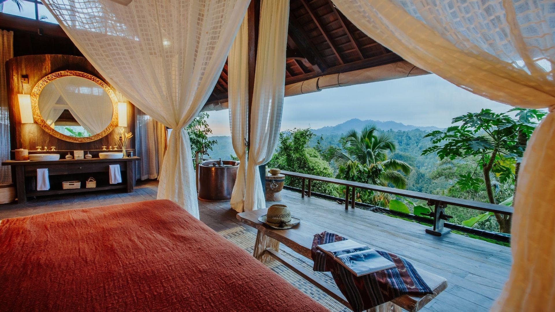 Luxurious canopy bed overlooks lush forest at Banyan Tree Escape - Buahan resort, offering serene views.