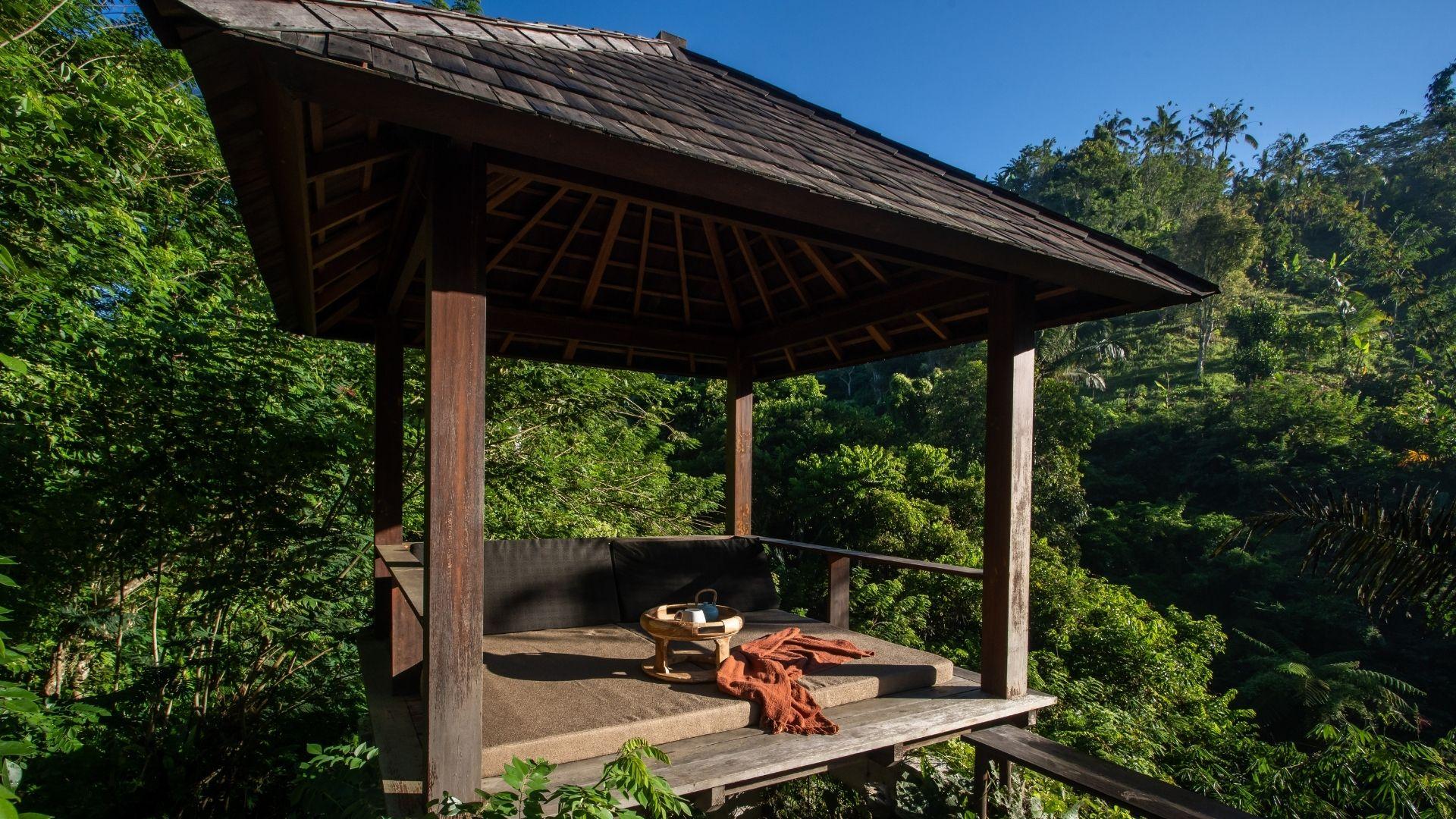 A wooden gazebo overlooks lush forest with a cozy seating area at Banyan Tree Escape - Buahan.