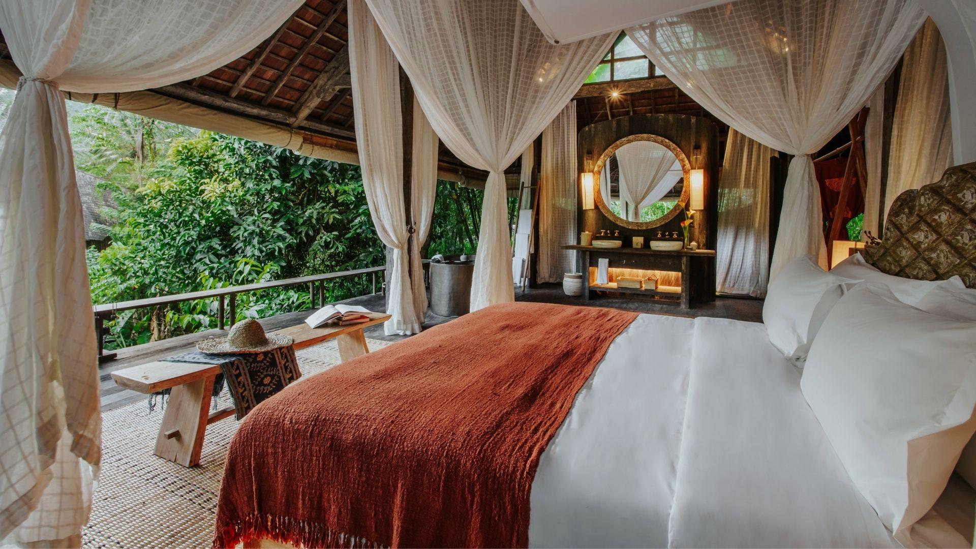 Luxurious bed draped in curtains, overlooking lush greenery at Banyan Tree Escape - Buahan.
