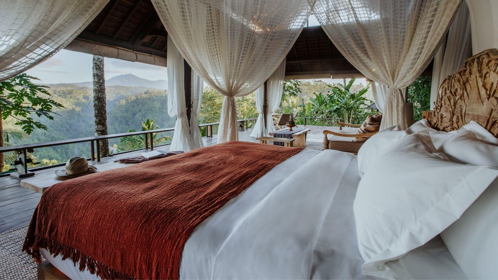 Cozy bed draped with netting overlooks lush forest & seven peaks view at Banyan Tree Escape - Buahan.