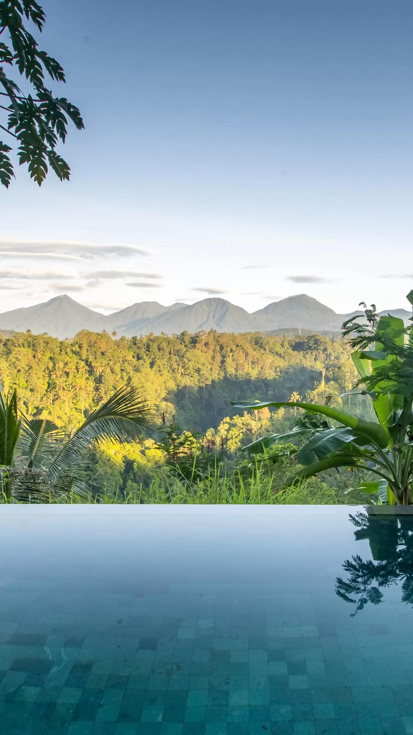 Infinity pool reflecting lush jungle view with mountains at Banyan Tree Escape - Buahan resort.