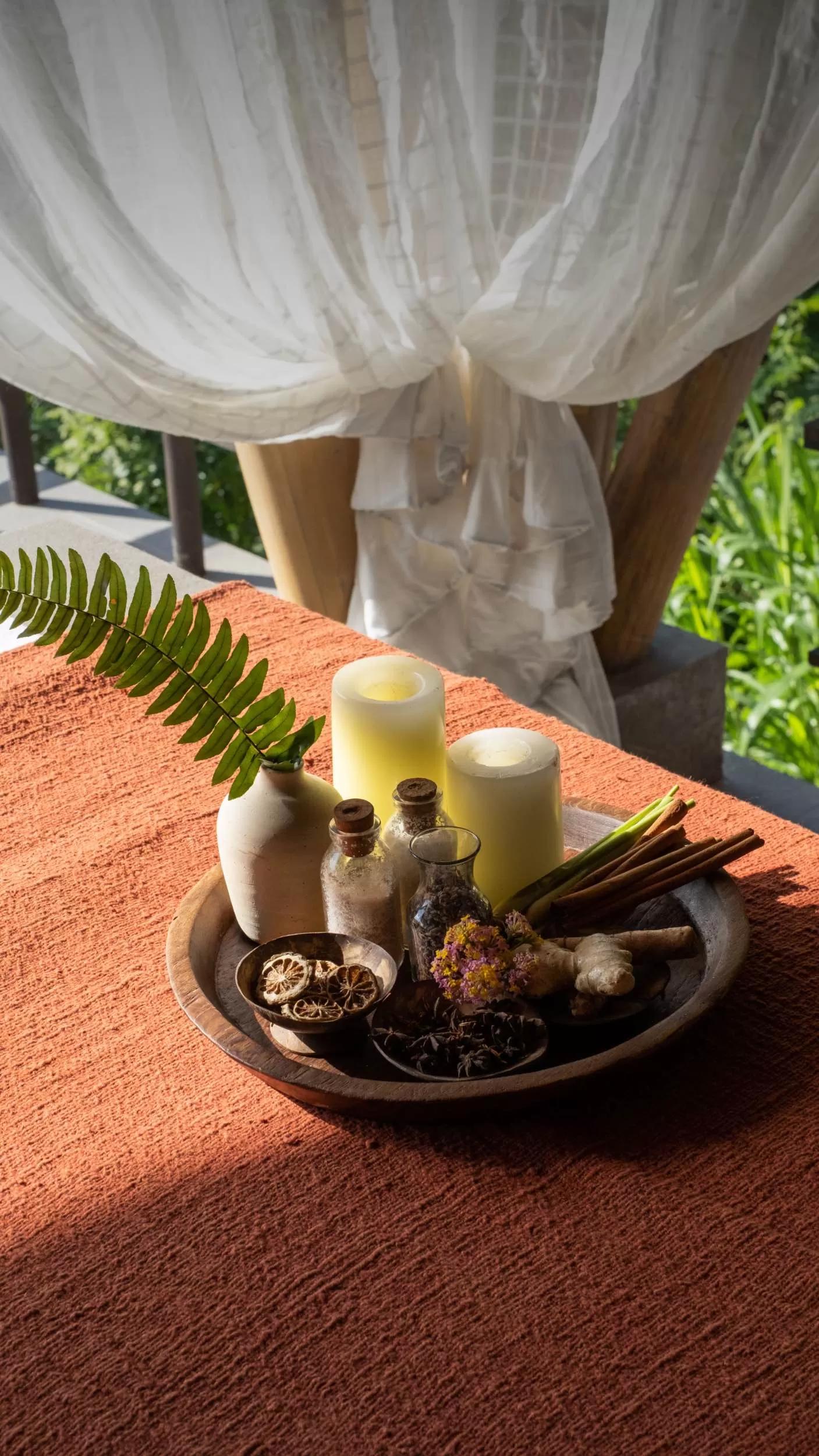 Candles and herbs sit in a tray on a sunlit table, Toja Spa, Banyan Tree Escape - Buahan