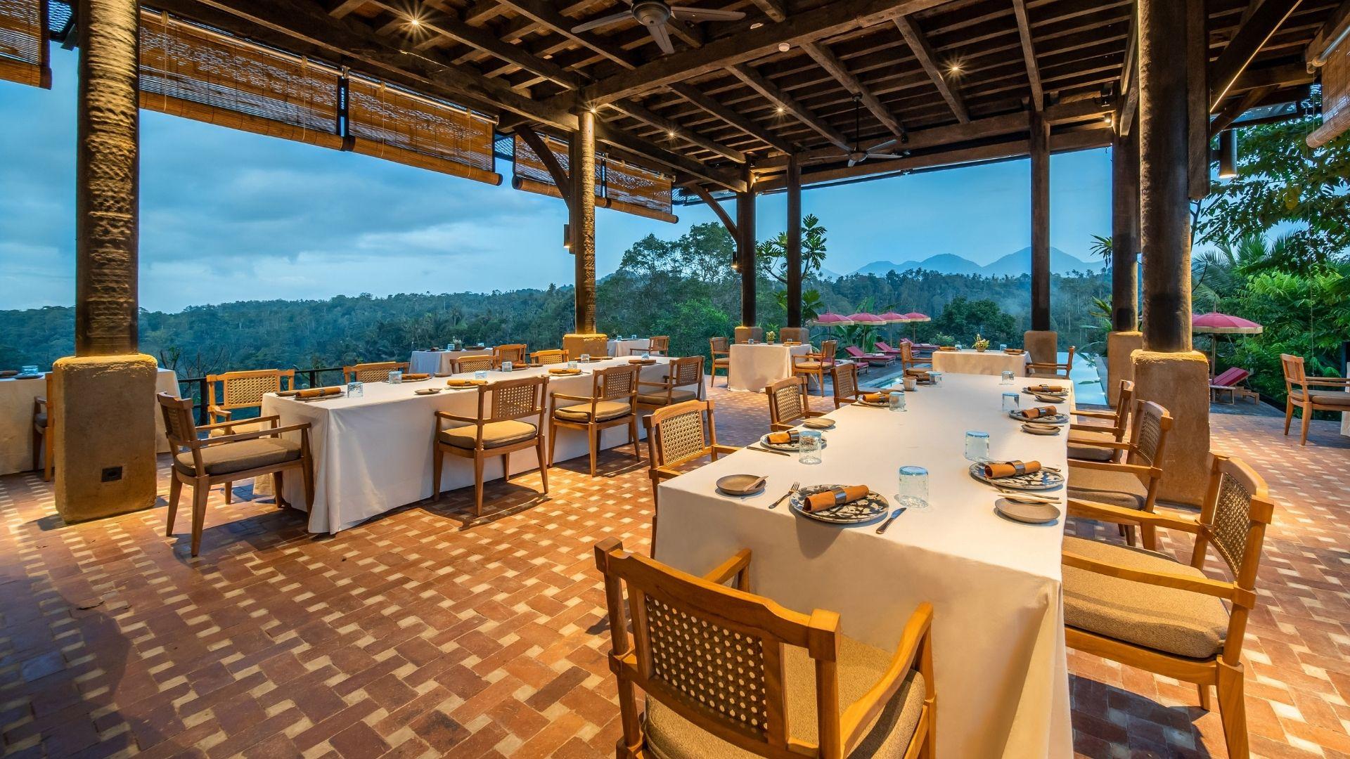 Open Kitchen Restaurant's dining tables set elegantly overlook lush forest and mountains, Banyan Tree Escape - Buahan.