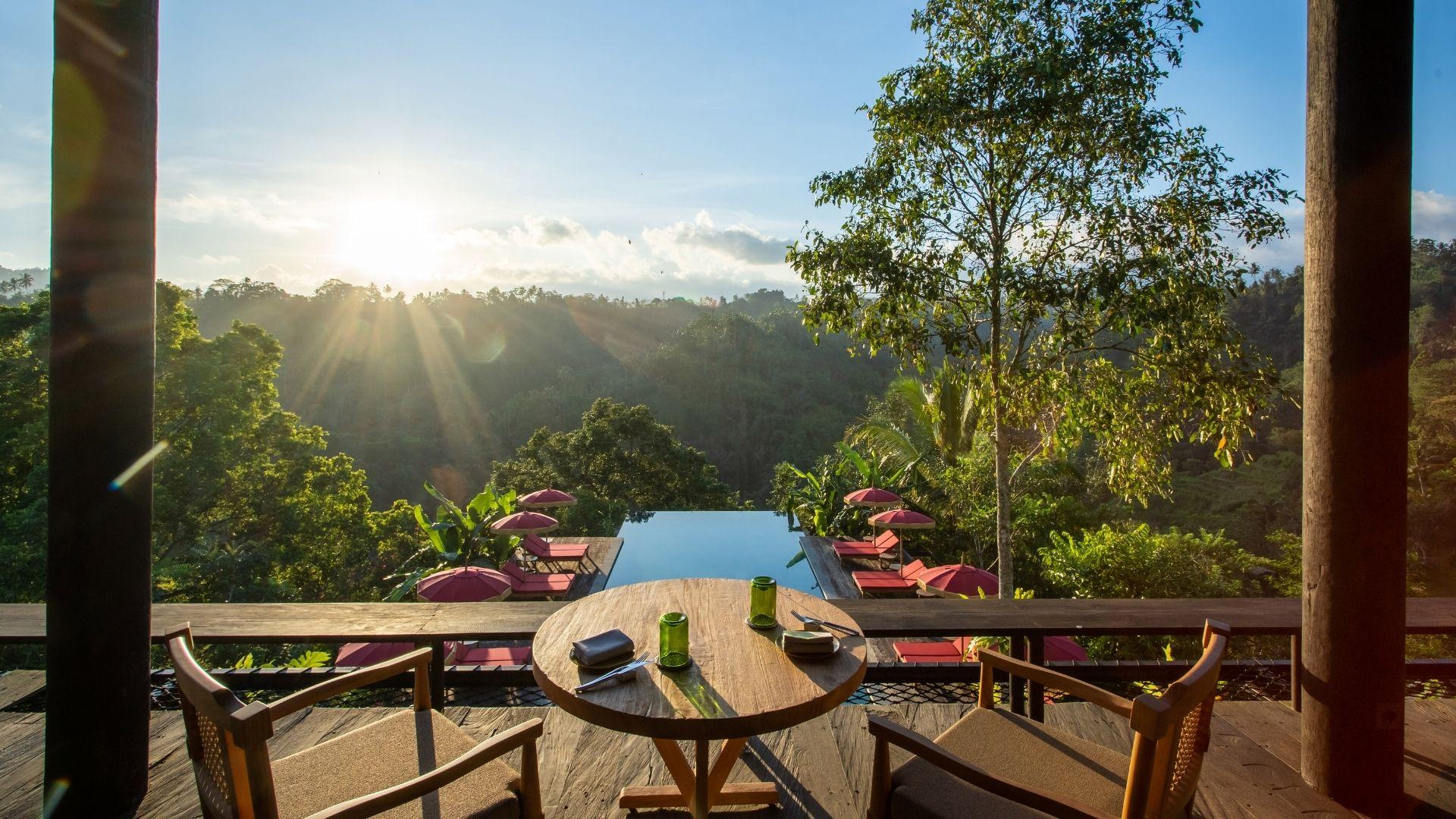 Table set with drinks at The Botanist bar, overlooks infinity pool and lush green valley at Banyan Tree Escape - Buahan.