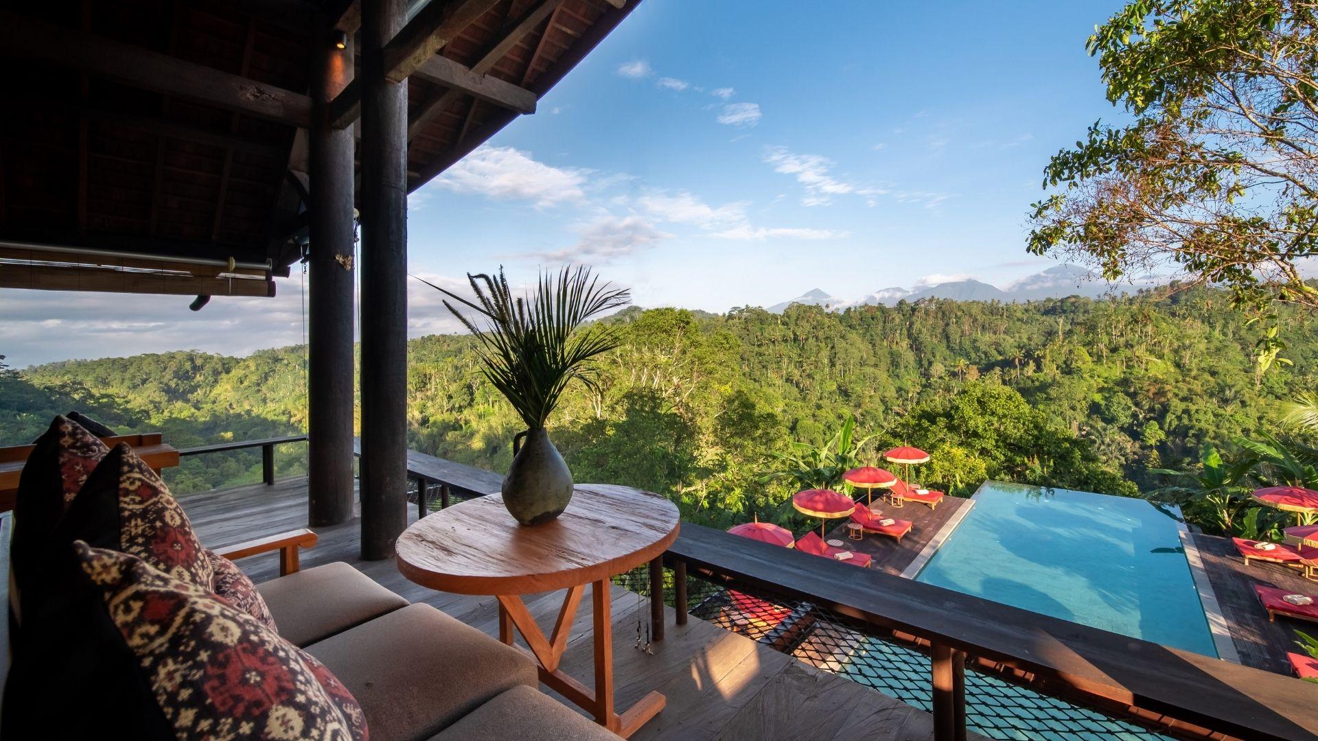 The Botanist bar lounge overlooks infinity pool and lush valley at Banyan Tree Escape - Buahan, with red umbrellas around.