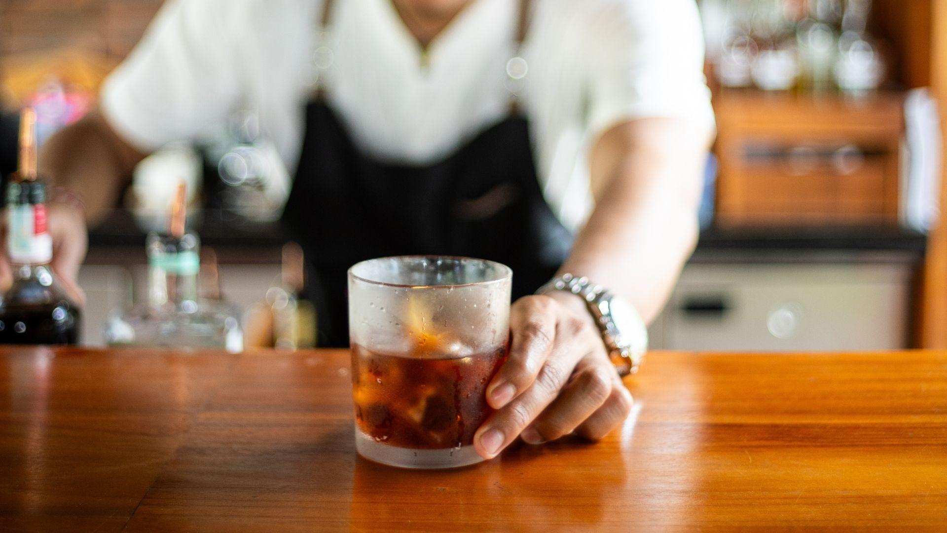 Bartender serves a cold drink  at The Botanist bar, Banyan Tree Escape - Buahan ambiance in background.