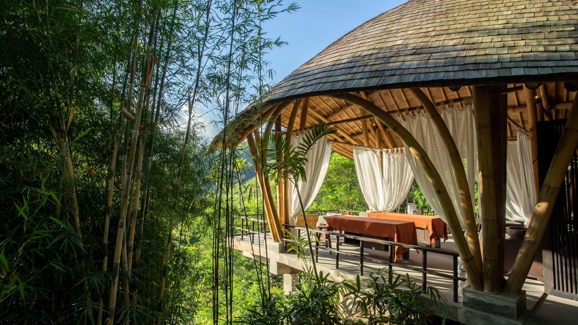 Bamboo pavilion with draped curtains at Buahan, a Banyan Tree Escape Spa, amid lush greenery.