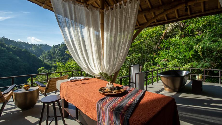 Toja Spa massage table set in lush, open-air pavilion of Banyan Tree Escape - Buahan, overlooking green valley.