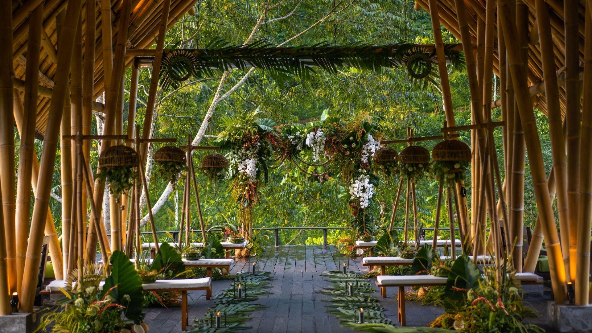 Wedding setting with bamboo structure adorned with lush florals, framed by greenery at Banyan Tree Escape - Buahan.