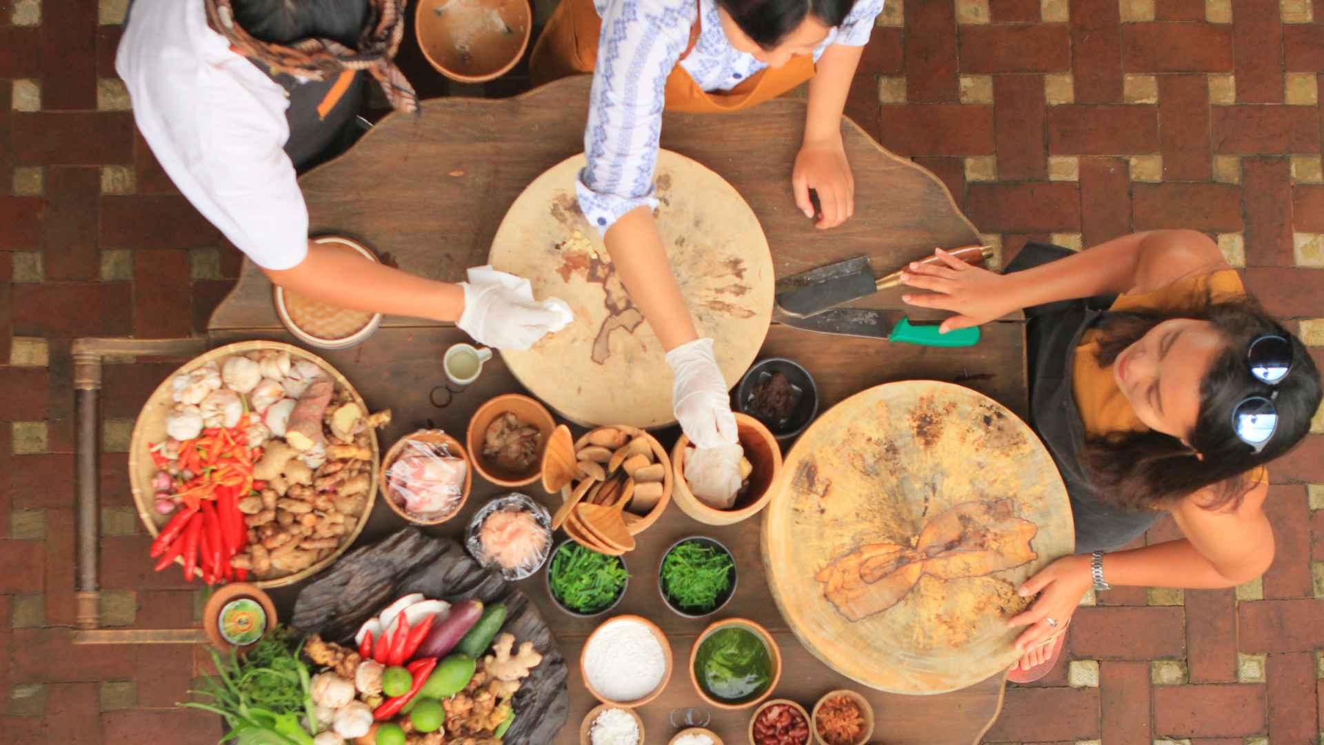 Chefs preparing ingredients on a wooden table at Banyan Tree Escape - Buahan, culinary experience.