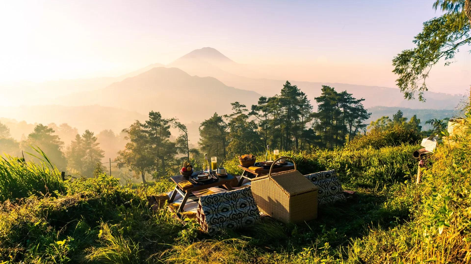 Picnic setup basking in sunrise atop a hill; Banyan Tree Escape - Buahan offers serene views of lavascape.