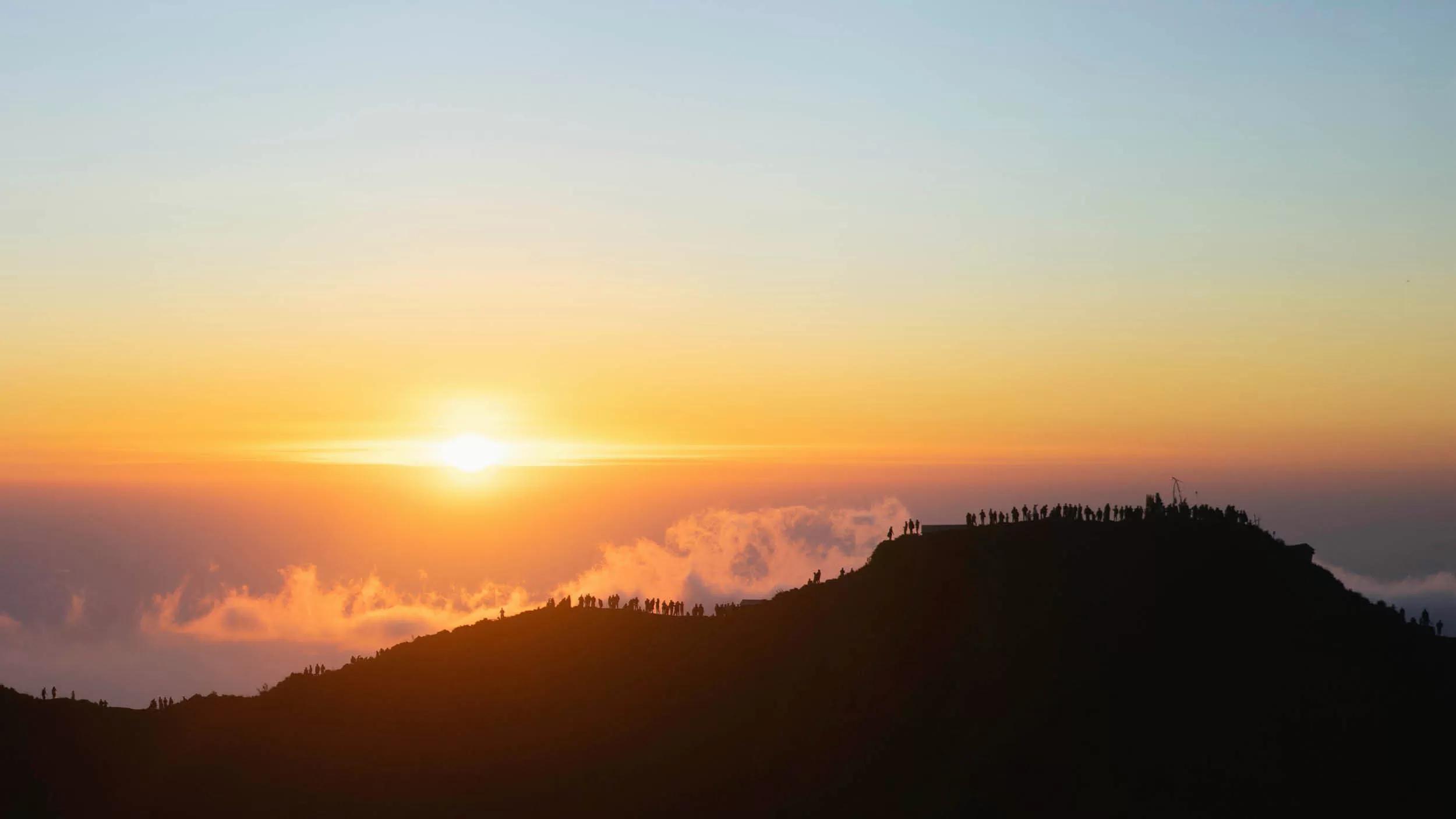 Sun rising over a silhouetted of Batur mountain hiking adventure, creating a serene scene at Banyan Tree Escape - Buahan.