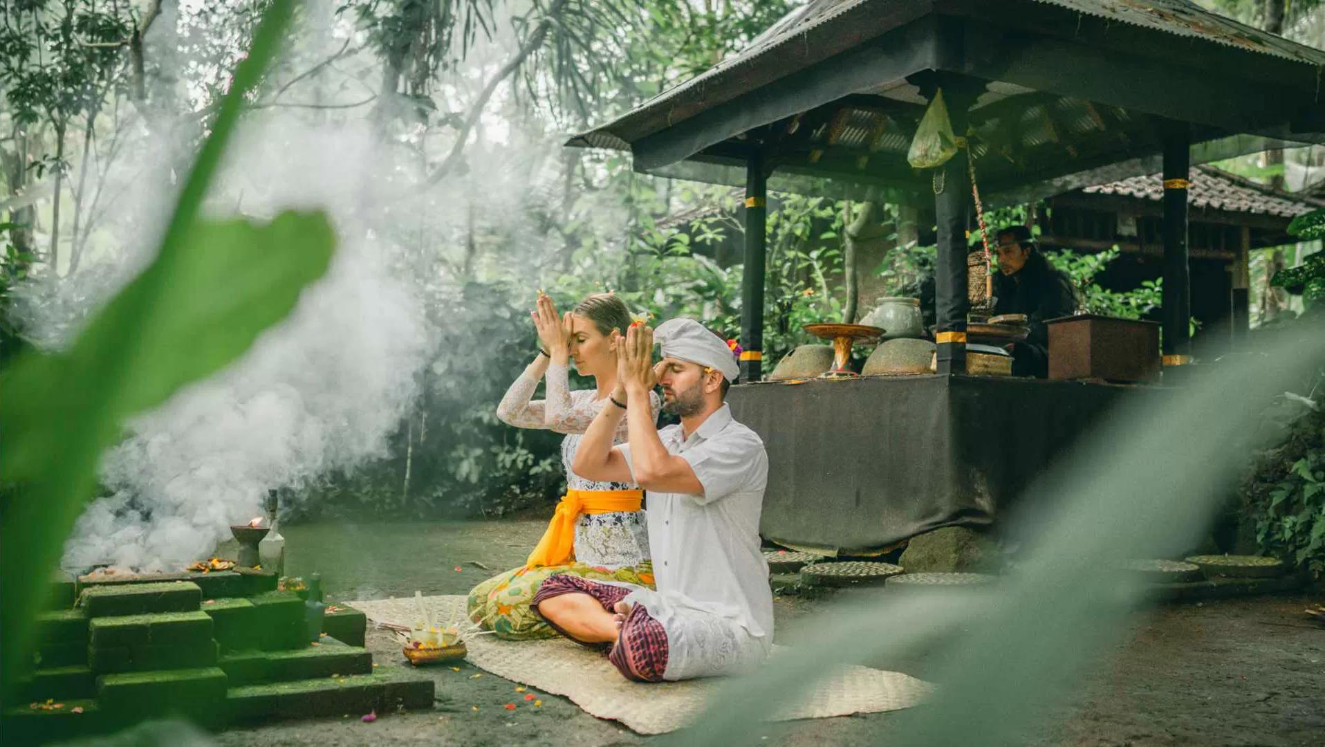 Two people meditate by temple, surrounded by jungle at Banyan Tree Escape - Buahan.