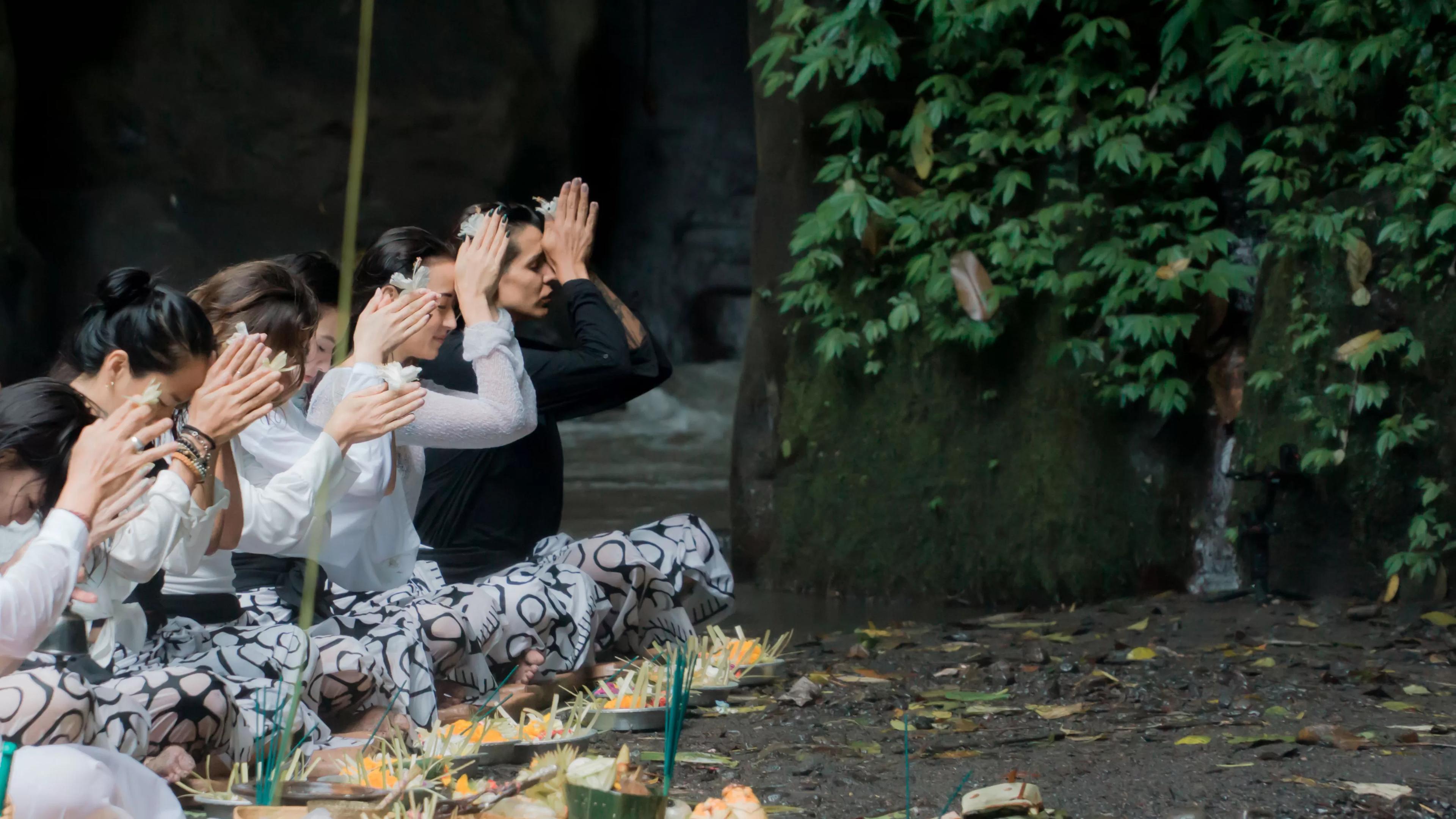 Individuals kneeling, praying in nature with greenery, part of Banyan Tree Escape - Buahan.
