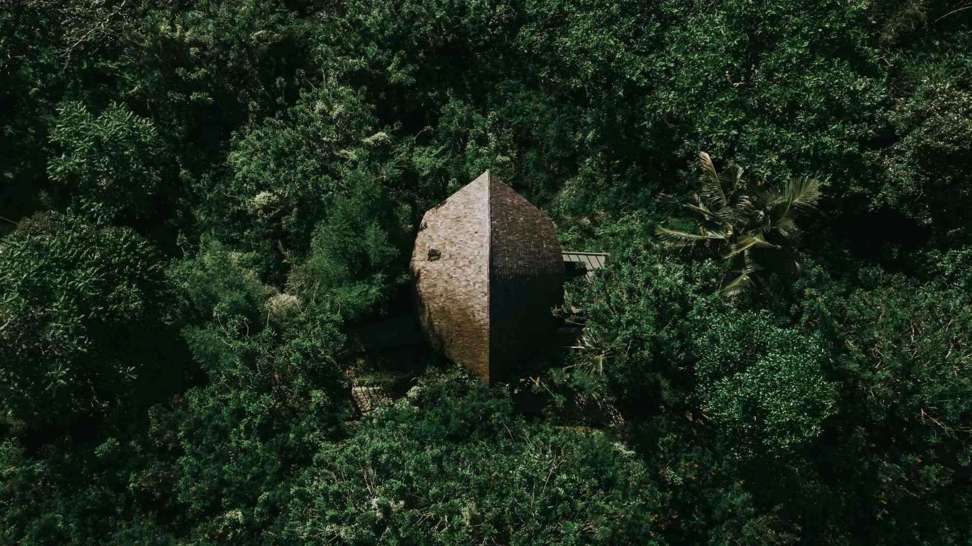 Rustic cabin nestled amid lush greenery at Banyan Tree Escape - Buahan, viewed from above.